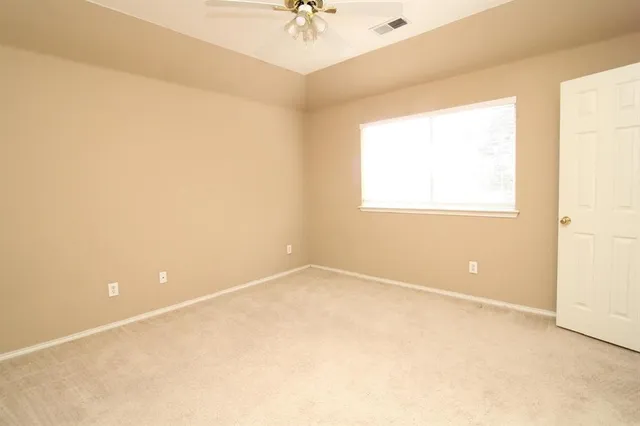 an empty room with a window and a ceiling fan
