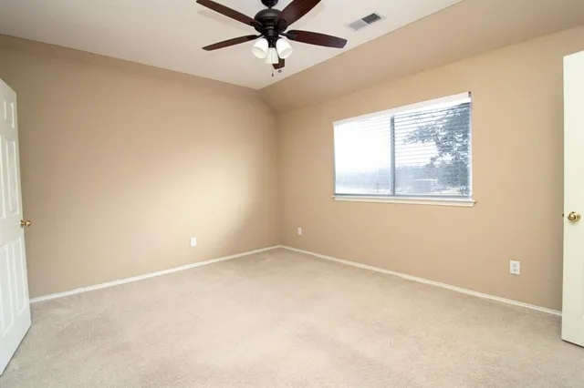an empty room with a window and a fan