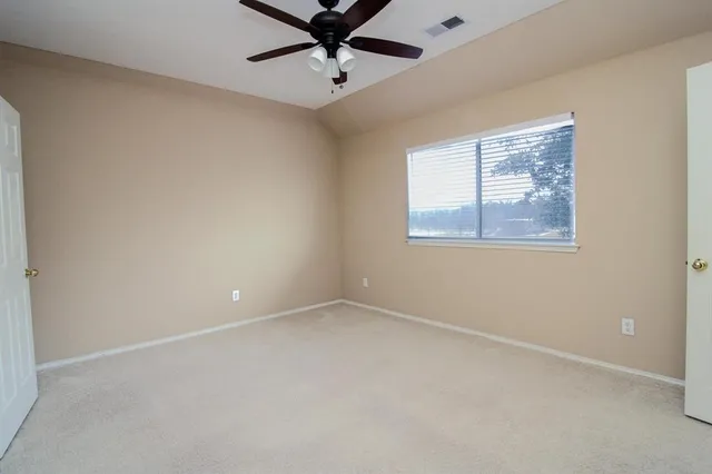 an empty room with a window and a fan
