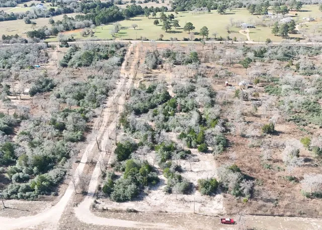 a view of a dry field with trees in background