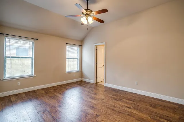 a view of an empty room with window and wooden floor