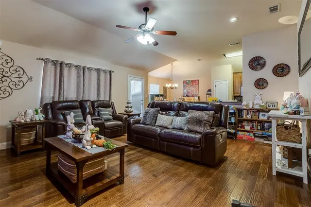 a living room with furniture kitchen view and a wooden floor
