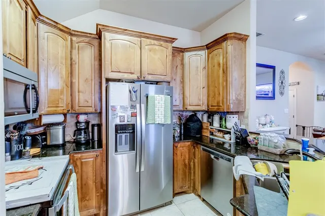 a kitchen with stainless steel appliances granite countertop a refrigerator a stove and a dining table view