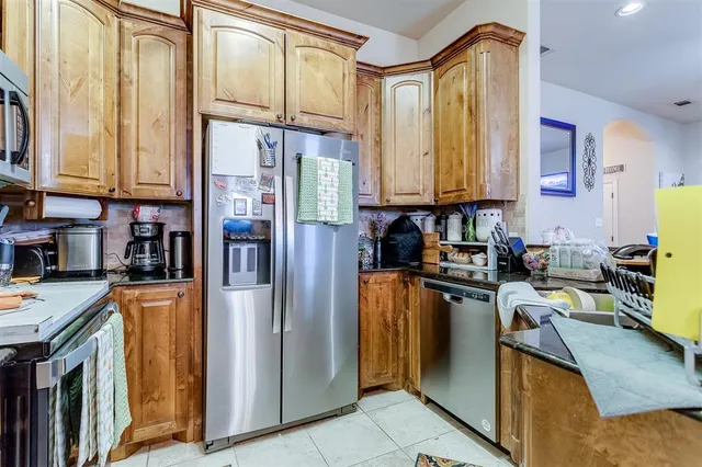 a kitchen with stainless steel appliances granite countertop a refrigerator a stove a sink and dishwasher