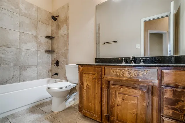 a bathroom with a granite countertop sink toilet mirror and bathtub