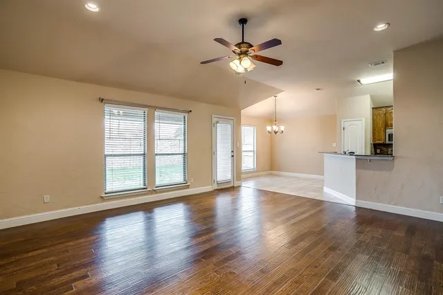 a view of an empty room with a window and wooden floor