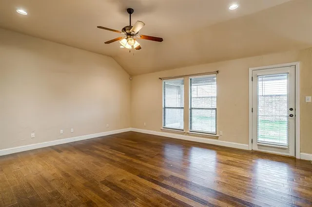 a view of an empty room with wooden floor and a window