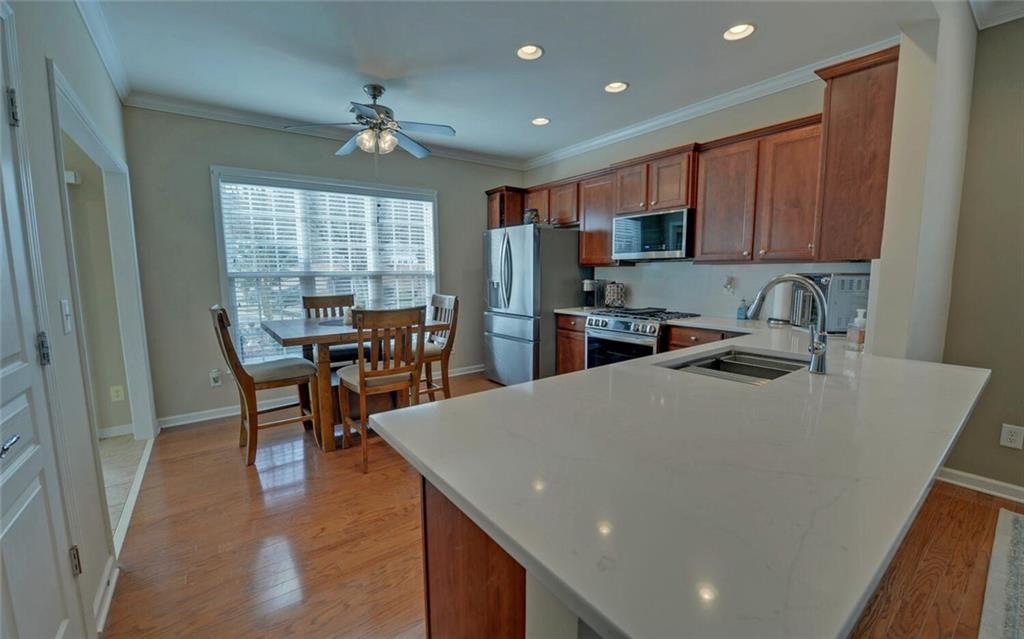 6213 Azalea Way Hoschton, GA 30548 - Photo 13 of 56 a kitchen with stainless steel appliances granite countertop a refrigerator a stove a sink a dining table and chairs with wooden floor