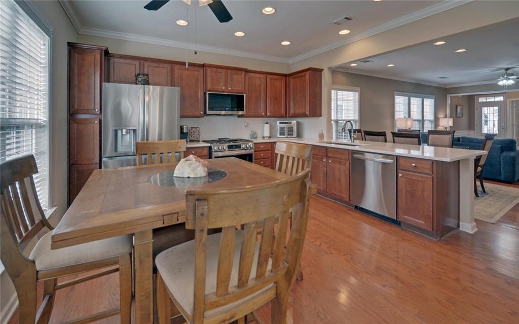6213 Azalea Way Hoschton, GA 30548 - Photo 14 of 56 a kitchen with stainless steel appliances granite countertop a sink a stove a refrigerator cabinets and a dining table with wooden floor