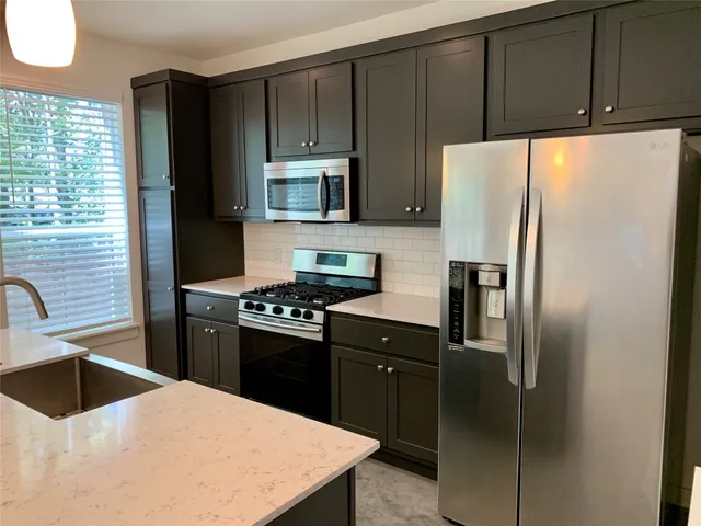 a kitchen with granite countertop a refrigerator stove and sink