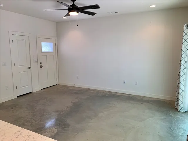 an empty room with a ceiling fan and window