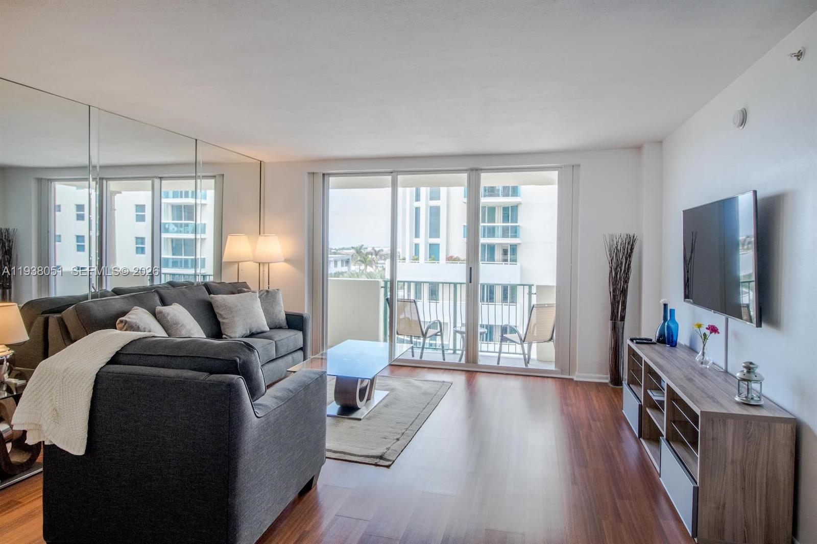 a living room with furniture a flat screen tv and a large window