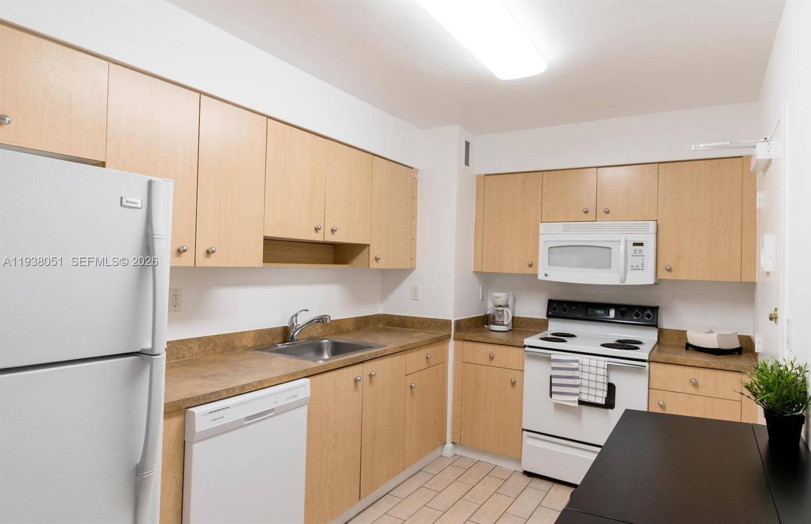 9195 Collins Avenue, Unit 611 Surfside, FL 33154 - Photo 10 of 33 a kitchen with white cabinets and white appliances
