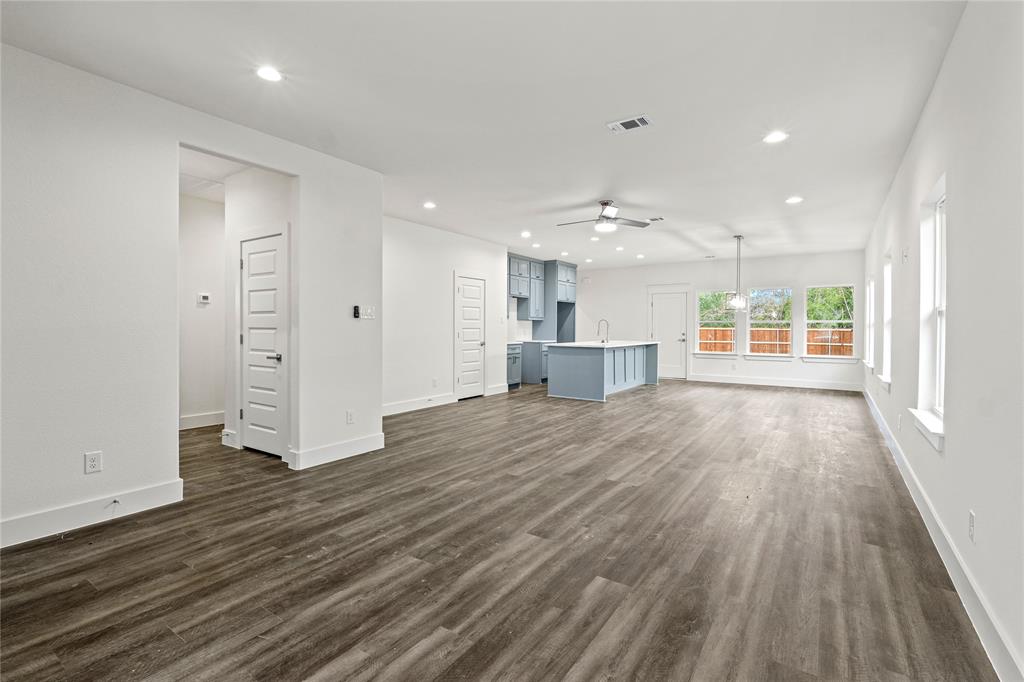 3335 Spring Avenue Dallas, TX 75215 - Photo 5 of 22 an empty room with wooden floor kitchen view and windows