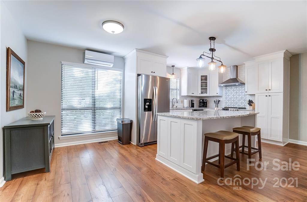 31016 Executive Point, Unit 15 Tega Cay, SC 29708 - Photo 7 of 35 a kitchen with stainless steel appliances granite countertop a refrigerator a sink dishwasher a stove and a dining table with wooden floor