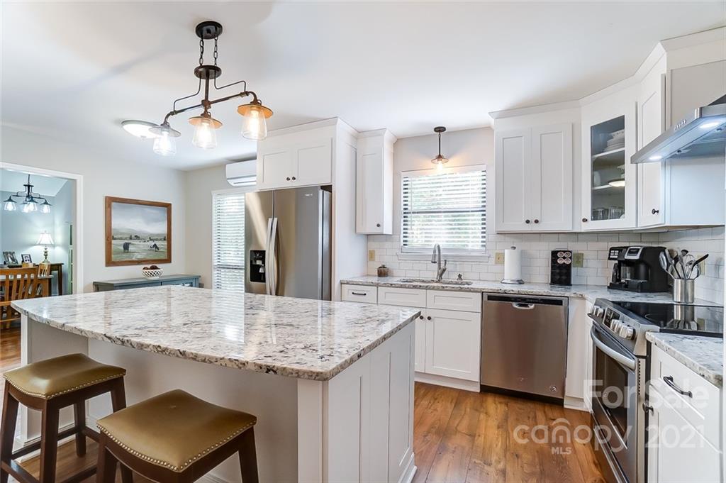31016 Executive Point, Unit 15 Tega Cay, SC 29708 - Photo 8 of 35 a kitchen with stainless steel appliances granite countertop a kitchen island hardwood floor sink stove dining table and chairs