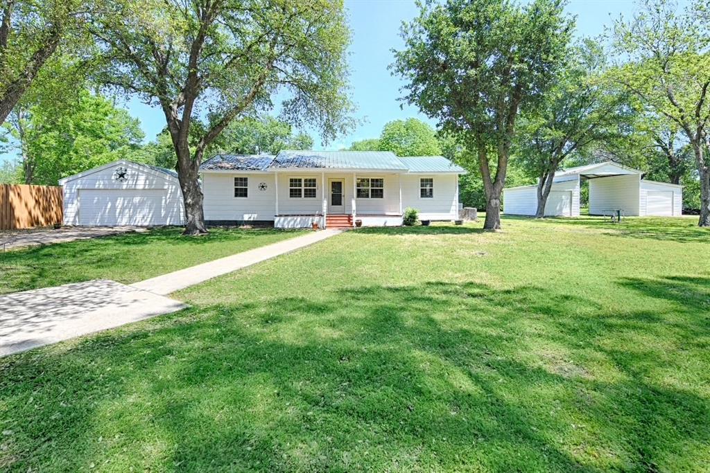 a front view of a house with a garden and trees