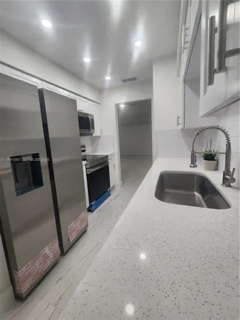 a kitchen with stainless steel appliances a sink a microwave a refrigerator and a sink
