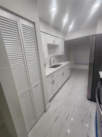 a large white kitchen with a sink a refrigerator and a stove