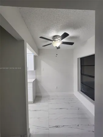 en empty room with a fireplace and ceiling fan