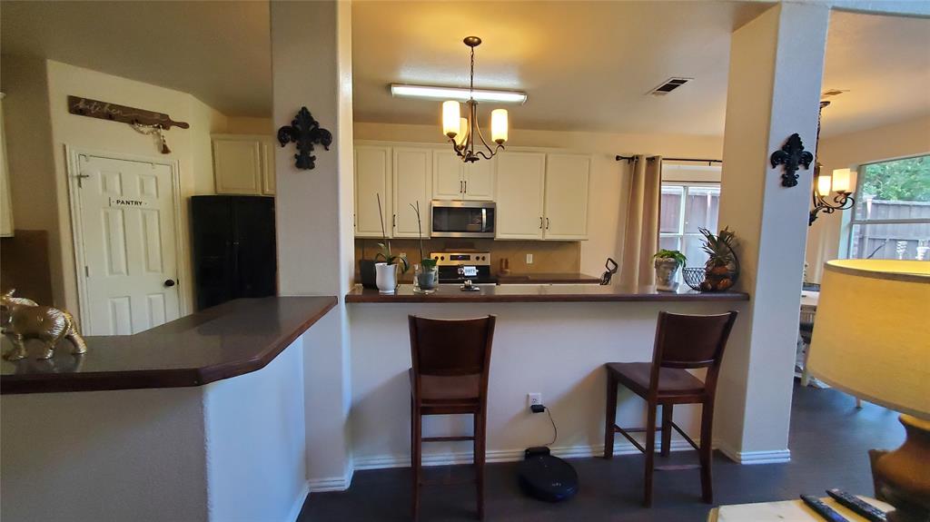 3416 Ridge Lily Lane McKinney, TX 75071 - Photo 10 of 32 Kitchen with dark countertops, stainless steel appliances, white cabinets, and a breakfast bar