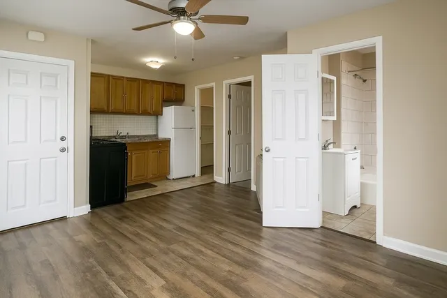 an empty room with wooden floor and a kitchen