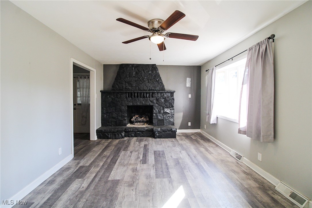 3267 South Leavitt Road Southwest Warren, OH 44481 - Photo 16 of 45 Unfurnished living room featuring wood finished floors, a fireplace, and ceiling fan