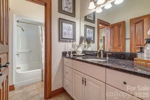 a bathroom with a granite countertop sink mirror and a bathtub