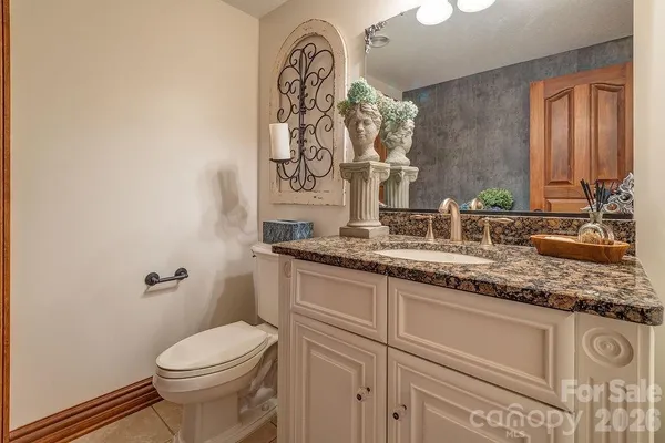 a bathroom with a granite countertop sink a toilet and mirror
