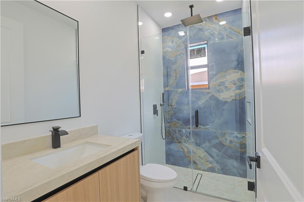 613-615 West 12th Street Lehigh Acres, FL 33972 - Photo 14 of 32 a bathroom with a granite countertop sink a toilet and shower