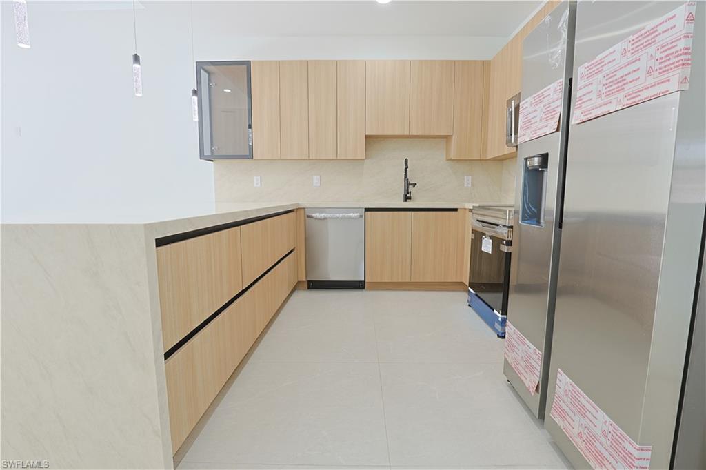 613-615 West 12th Street Lehigh Acres, FL 33972 - Photo 4 of 32 a kitchen with a refrigerator sink stove and cabinets