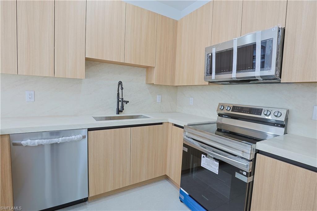613-615 West 12th Street Lehigh Acres, FL 33972 - Photo 5 of 32 a kitchen with stainless steel appliances a stove microwave and sink