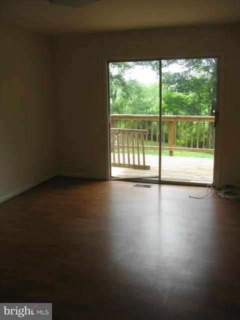 17981 Possum Point Road Dumfries, VA 22026 - Photo 2 of 27 a view of an empty room with wooden floor and a floor to ceiling window
