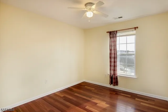 an empty room with wooden floor fan and windows