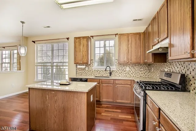 a kitchen with granite countertop a sink a counter space appliances and cabinets