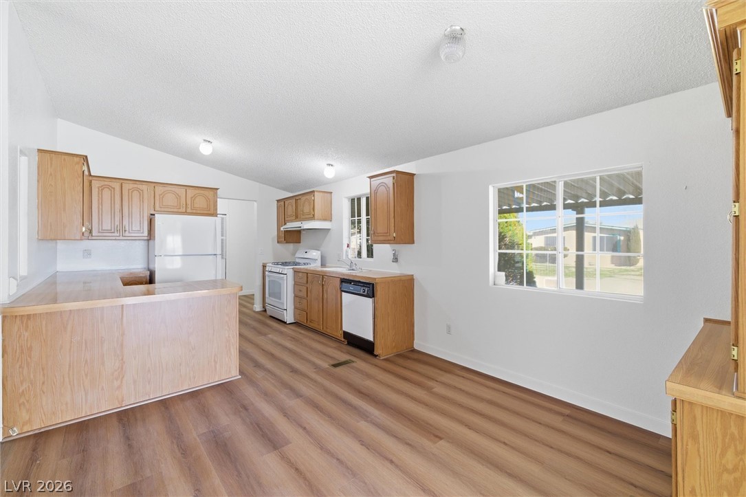 20 Rudy Road Pahrump, NV 89048 - Photo 13 of 32 Ample wooden cabinetry and wood-look flooring define this functional kitchen layout.