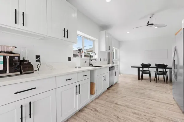 a kitchen with white cabinets sink and chairs