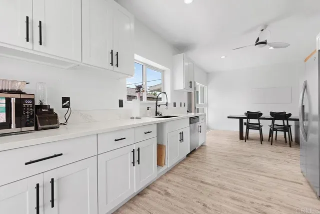 a kitchen with white cabinets sink and chairs