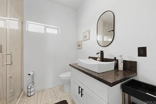 a bathroom with a granite countertop sink a toilet and a mirror