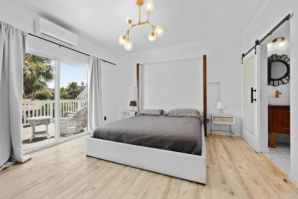 a living room with a bed large window and a wooden floor
