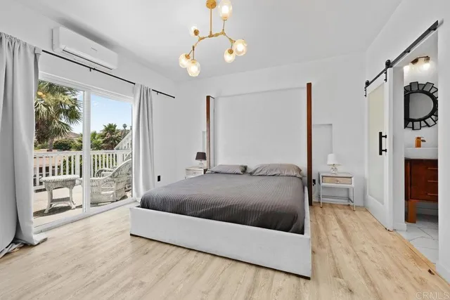 a living room with a bed large window and a wooden floor