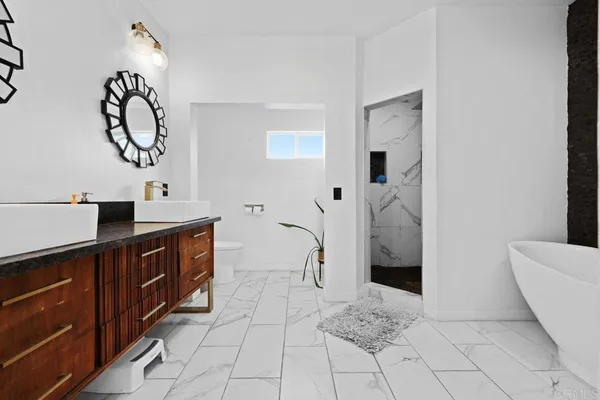 a spacious bathroom with a double vanity sink a toilet and a mirror