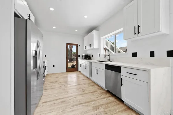 a large white kitchen with stainless steel appliances