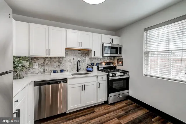 a kitchen with granite countertop white cabinets and stainless steel appliances