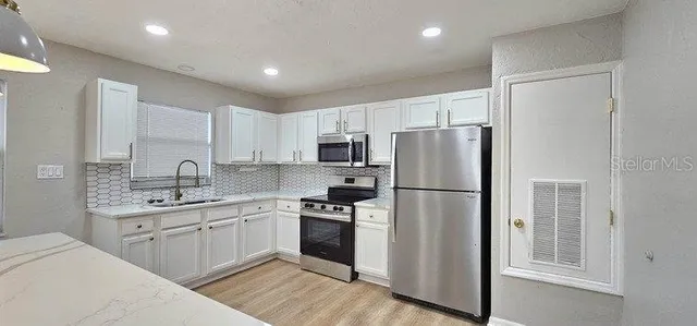 a kitchen with granite countertop a refrigerator and white cabinets