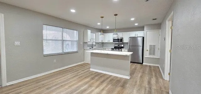 a kitchen with granite countertop a stove a sink and a refrigerator