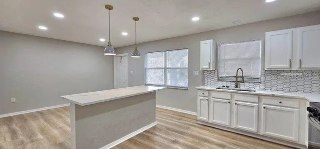 a room with kitchen island a sink stainless steel appliances and cabinets