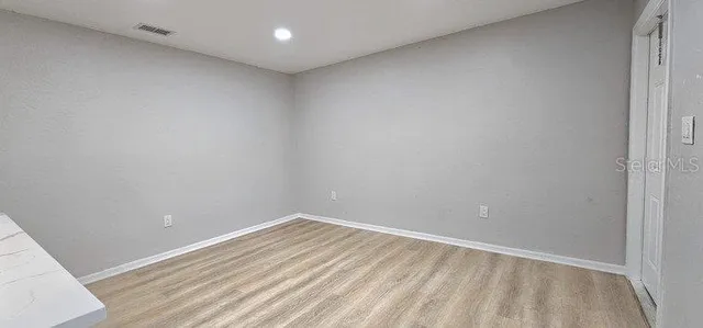 an empty room with wooden floor and a ceiling fan