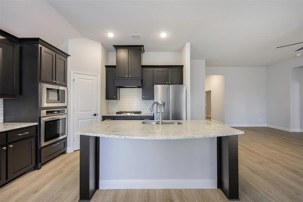 226 Comanche Trail Alvarado, TX 76009 - Photo 9 of 28 a large kitchen with stainless steel appliances kitchen island granite countertop a refrigerator a stove a sink and a granite countertops with wooden floor