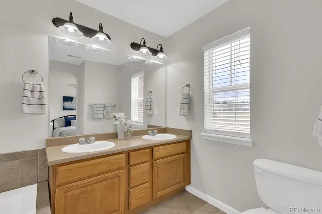a bathroom with a granite countertop sink a toilet a mirror and a window
